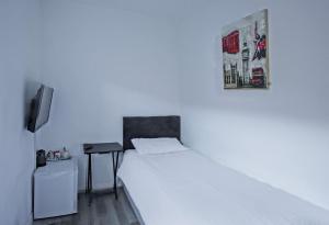 a white bedroom with a bed and a tv at OYO Aparthotel Hathern in Hathern