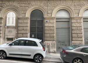una macchina bianca parcheggiata di fronte a un edificio di Center Monflat a Trieste