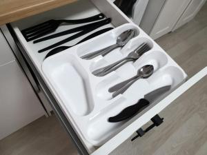 a white tray with silver utensils in a drawer at Милая Студия 2 in Atyrau