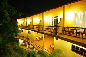 un edificio de apartamentos con balcón con mesas y sillas en Laluna Ayurveda Resort, en Bentota