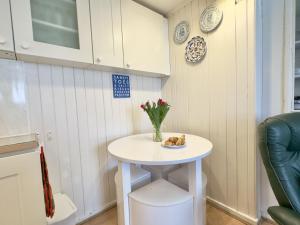 una pequeña mesa blanca en una cocina con un jarrón de flores en Little Penty en Padstow