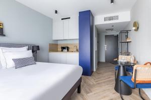 a bedroom with a bed and a table and a kitchen at Appart'City Collection Paris Roissy CDG Airport in Roissy-en-France