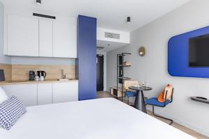 ein Schlafzimmer mit einem weißen Bett und einer blauen Wand in der Unterkunft Appart'City Collection Paris Roissy CDG Airport in Roissy-en-France