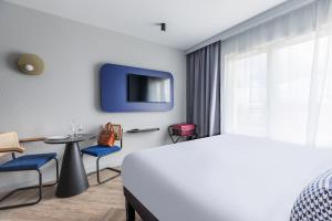 ロワシー・アン・フランスにあるAppart'City Collection Paris Roissy CDG Airportのベッドとテレビ付きのホテルルーム
