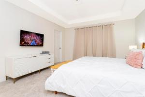 1 dormitorio blanco con 1 cama y TV en la pared en 1798 TP - 4BR Luxury Solara Retreat Pool Disney, en Orlando