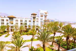 um grande edifício branco com palmeiras em frente em Bloom - Marina Agadir - Piscine - 4 or 5 Px em Agadir