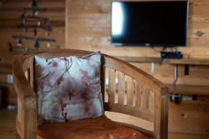 a wooden chair with a pillow in front of a television at Šumska priča Tara / A Forest Tale Tara in Mokra Gora