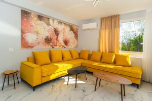 um sofá amarelo numa sala de estar com um quadro em ENEVI Guest Houses em Sandanski