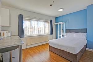 a bedroom with a bed with blue walls and a kitchen at OYO Aparthotel Hathern in Hathern