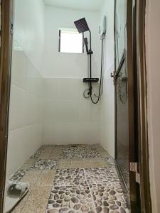 a bathroom with a shower and a tiled floor at MHARI Bungalows & Studio Rooms in Tubod
