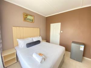 um quarto com uma grande cama branca com toalhas em Cumberland Guest Lodge em Bulawayo