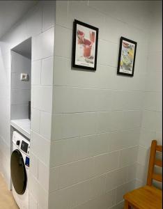 Una lavadora y secadora en un baño con dos cuadros en la pared en Casa los Geranios, en Arcos de la Frontera