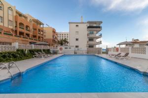 a swimming pool with chairs and a building at RentitSpain Arce 1-13 Vista a la playa del mar Mediterráneo in Nerja