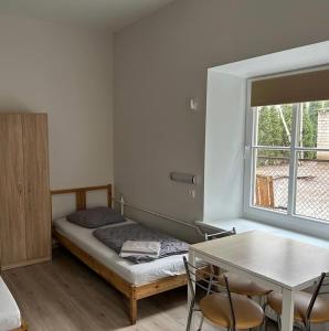 1 dormitorio con cama, mesa y ventana en Hostel Filaretai, en Vilna