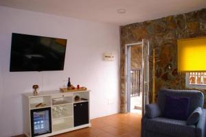 a living room with a tv and a chair at Vivienda Vacacional Cuenca de Liria in Hermigua