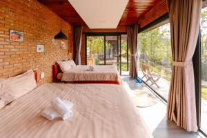 two beds in a room with a large window at Scent Bungalow - Village in Da Lat