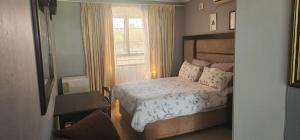 een kleine slaapkamer met een bed en een raam bij I B B Guesthouse in Pinetown