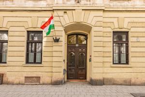 a building with a flag in front of a door at Amber Gardenview Studios Downtown in Budapest