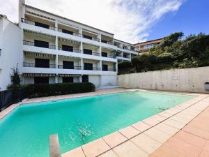 LA BAIE Studio cabine climatisé, vue mer, pour 4 personnes avec piscine sur la presqu'île de Giens à Hyères في هييريس: مسبح فارغ امام مبنى