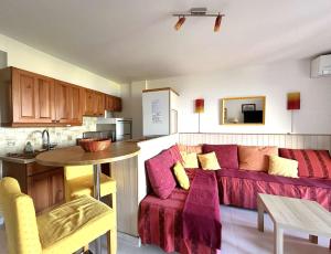 sala de estar con sofá rojo y cocina en LA BAIE Studio cabine climatisé, vue mer, pour 4 personnes avec piscine sur la presqu'île de Giens à Hyères, en Hyères