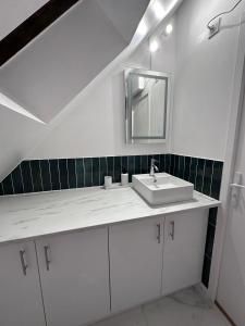uma casa de banho branca com um lavatório e um espelho em Le Nid Douillet - Hypercentre - Studio em Beauvais