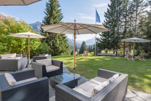 a patio with chairs and a table with an umbrella at Valbella-Lenzerheide Youth Hostel in Lenzerheide
