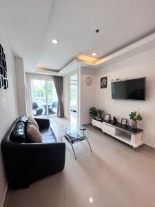 sala de estar con sofá negro y TV en Cosy Beach View Condominium en Pattaya South