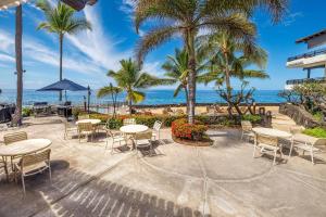 a patio with tables and chairs and the beach at Casa De Emdeko 330 in Kailua-Kona
