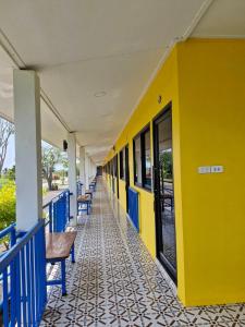 a yellow and blue building with benches on it at Yungthong Baan Suan Resort in Ban Ko
