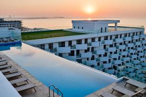 een overloopzwembad op het dak van een gebouw met zonsondergang bij AdeMar Luxury Apartment- Spa&Pool Beach Resort in Mamaia