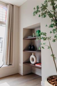 una sala de estar con una planta y estanterías en The Guest Apartments - Lange Putstraat en Den Bosch