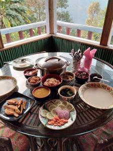 a table with plates and bowls of food on it at Red Panda Eco Huts, Kolakham in Lava