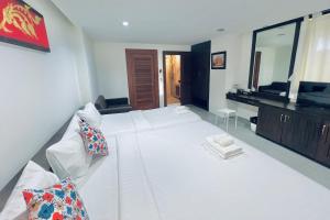 a large white bed in a room with a television at De Nawarat Chiangmai Boutique Apartment in Chiang Mai