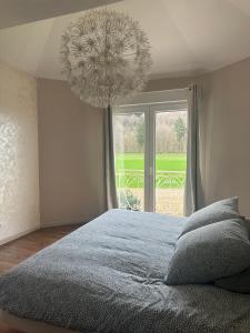 een slaapkamer met een groot bed en een kroonluchter bij Maison familiale avec vue dégagée in Vaux-lès-Prés
