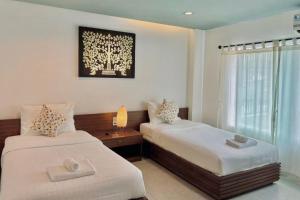 a bedroom with two beds and a window at De Nawarat Chiangmai Boutique Apartment in Chiang Mai
