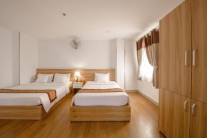 two beds in a room with wooden floors at Palago Park View Hotel in Ho Chi Minh City