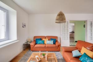 ein Wohnzimmer mit einem orangenen Sofa und blauen Kissen in der Unterkunft Détente et découverte du Pays Bigouden in Plonéour-Lanvern
