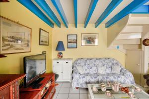 ein Wohnzimmer mit einem Sofa und einem TV in der Unterkunft Vacances en famille à Ile-Tudy in Île-Tudy