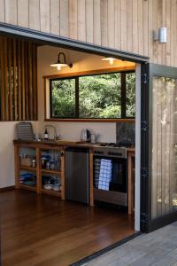 an open kitchen with a counter and a window at Modern, Cosy Hideaway - Rua Nuka Raglan in Raglan