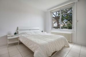 a white bedroom with a bed and a window at Détente tout près de la plage de Sainte-Marguerite in Pornichet