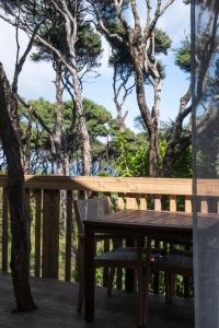 a wooden bench sitting on a deck with trees at Modern, Cosy Hideaway - Rua Nuka Raglan in Raglan