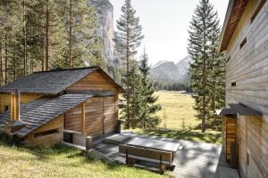 a wooden cabin with a bench next to a building at Mountain Lodge Tamersc in San Vigilio Di Marebbe