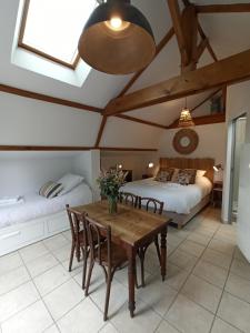 a bedroom with two beds and a wooden table and chairs at Le Cottage des Falaises in Gonneville-sur-Mer