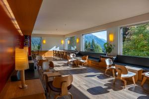 a restaurant with tables and chairs and large windows at Valbella-Lenzerheide Youth Hostel in Valbella