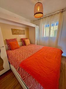 - une chambre avec un lit doté de draps orange et une fenêtre dans l'établissement Rousseau, à Théoule-sur-Mer