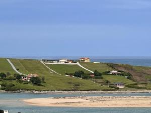 a beach with houses on a hill next to the ocean at Apartamento La Caleta III - Monabri in Mogro