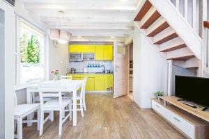 kuchnia i jadalnia z żółtymi szafkami oraz stołem i krzesłami w obiekcie Bedroom - domek nr 2 w Łebie