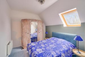um quarto com uma cama azul e uma janela em Repos, détente et découverte du Pays Bigouden em Penmarcʼh
