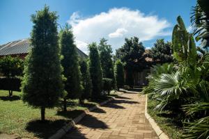 un jardín con árboles y una pasarela de ladrillo en Mahafaly Hotel & Resort, en Antsirabe