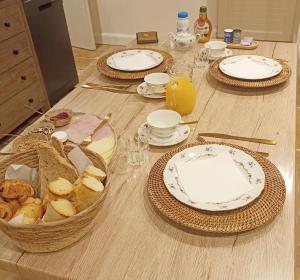 una mesa con platos y cestas de pan y zumo de naranja en Chambre d'hôtes Au Petit Bonheur, en Lorigné